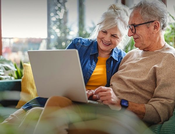 Couple smiling while reviewing plans on a laptop at home