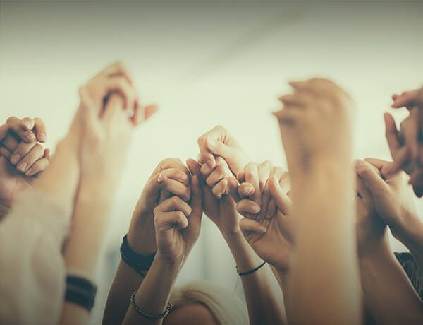 Group of people raising joined hands together